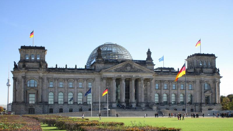 Bild des Reichstages, Sitz des Deutschen Bundestages, beflaggt und unter blauem Himmel